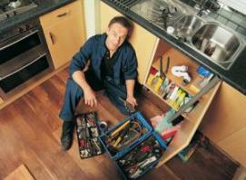 technician makes repairs in a sink cabinet